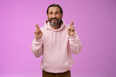 Portrait of man standing against pink background