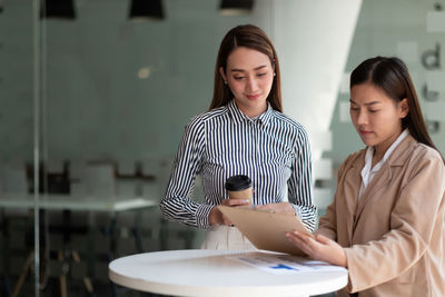 Portrait of young woman using digital tablet while sitting at office