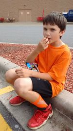 Portrait of boy eating food on road