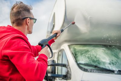 Side view of man cleaning car with hose