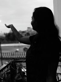 Side view of woman gesturing while standing in balcony
