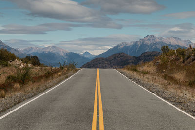 Road leading towards mountains against sky