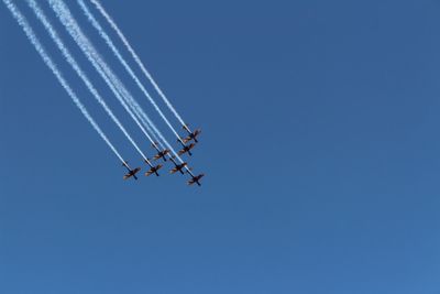 Low angle view of airshow against clear blue sky