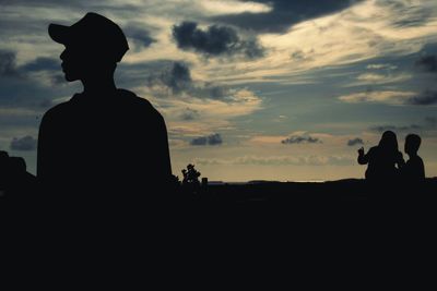 Rear view of silhouette man and woman against sunset sky