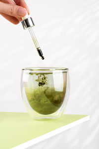 Female hand pours liquid chlorophyll into a glass of water with dropper. glass of liquid chlorophyl