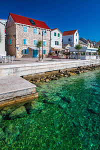 Buildings by river against sky