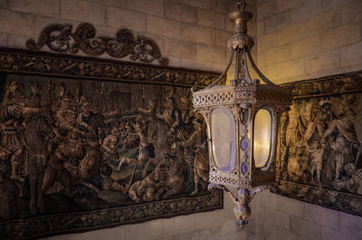 Old lamp hanging by paintings on wall of castle
