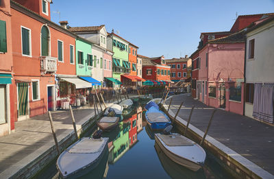 Boats moored in canal amidst buildings against sky
