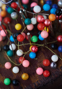 High angle view of colorful beads and metal with thread on fabric