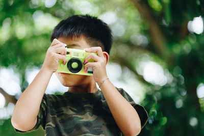 Boy playing with toy camera at park