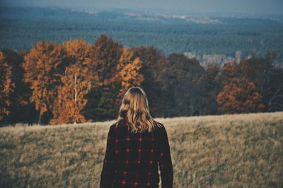 Rear view of man standing on field by autumn trees