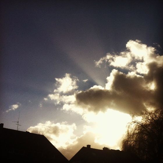 low angle view, sky, building exterior, built structure, architecture, silhouette, cloud - sky, cloud, house, sunset, sunlight, cloudy, high section, sun, sunbeam, nature, outdoors, beauty in nature, no people, building