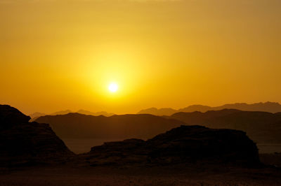 Scenic view of silhouette mountains against orange sky