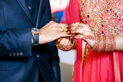 Midsection of couple holding hands during wedding ceremony