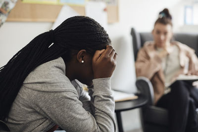 Depressed female student discussing with counselor in school office