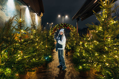 Young woman enjoying festive christmas tree display at night