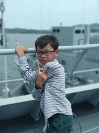 Portrait of boy standing by railing
