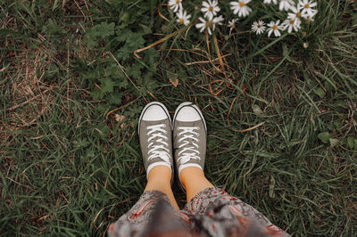 Women's legs in a long dress and green sneakers on the autumn withered grass. autumn mood picture
