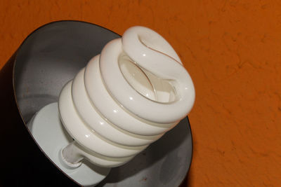 High angle view of illuminated light bulb on table against wall