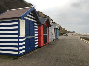 Beach huts by buildings against sky