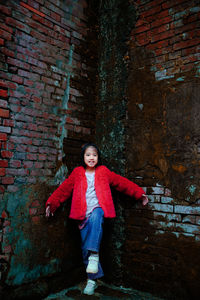 Portrait of smiling girl standing against brick wall