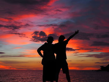 Silhouette men standing against sky at sunset