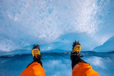 Low section of person against snowcapped mountains during winter