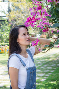 Portrait of beautiful woman standing by flowering plants