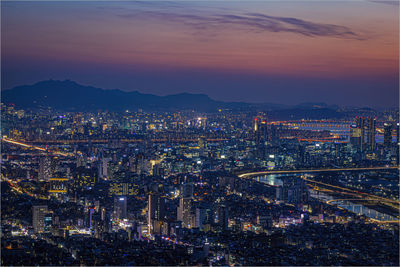 High angle view of illuminated city against sky at sunset