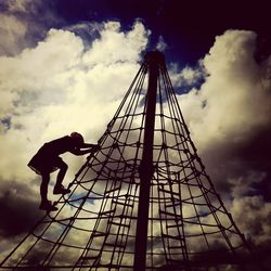 Low angle view of ferris wheel against cloudy sky