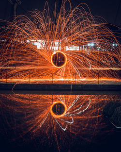 Person spinning wire wool reflecting in calm water