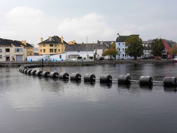 Buildings by river against sky