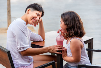 Mother and daughter having fun drinking milkshake