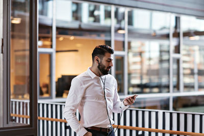 Young man looking away while standing against railing