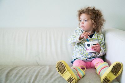 Cute girl sitting on sofa at home