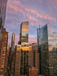 Modern buildings in city against sky during sunset