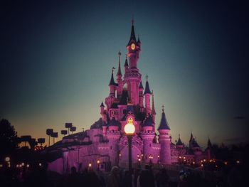 People at illuminated temple against clear sky at night