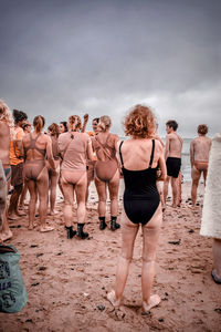 Rear view of people at beach against sky