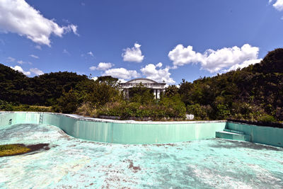 Swimming pool by trees against sky