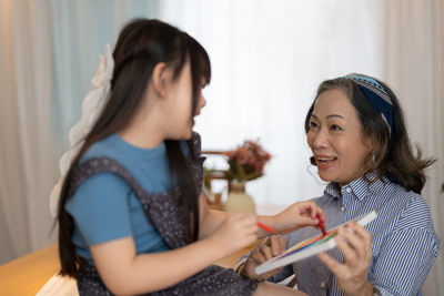 Happy woman with crayons looking at daughter