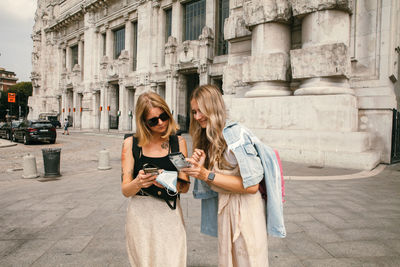 Portrait of smiling young woman standing against building