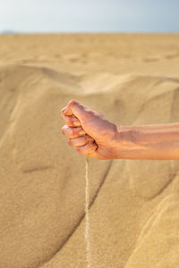 Midsection of person on sand at beach against sky