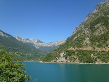 Scenic view of lake and mountains against clear blue sky