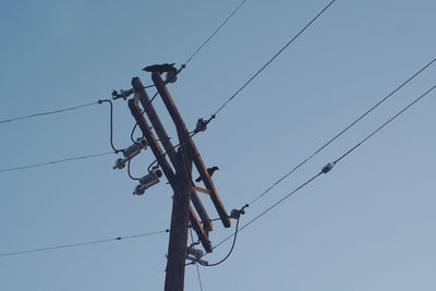 Low angle view of power lines against clear blue sky