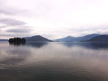 Scenic view of lake by mountains against sky