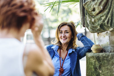 Cheerful mature woman with friend in park