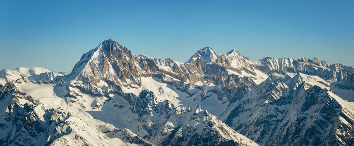 Panoramic view of snowcapped mountains against clear blue sky