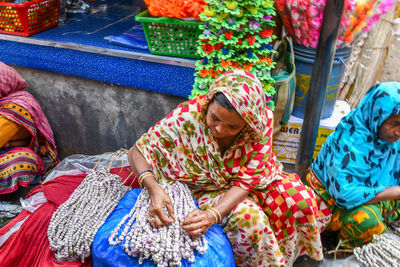 Midsection of woman holding colorful while sitting in market