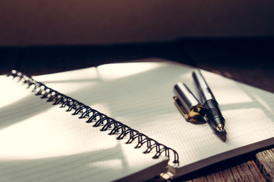 High angle view of pen and book on wooden table