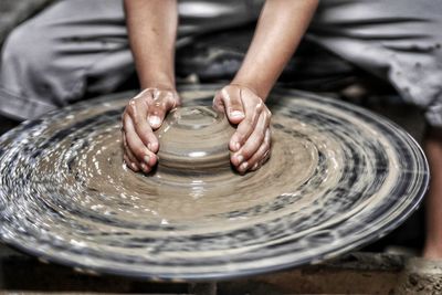 Cropped hands of potter making earthenware on pottery wheel